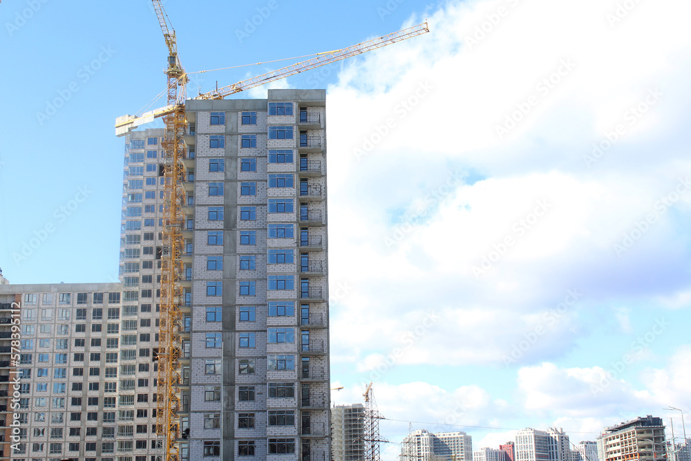 construction of apartament against the blue sky. construction site with crane. big building in the city