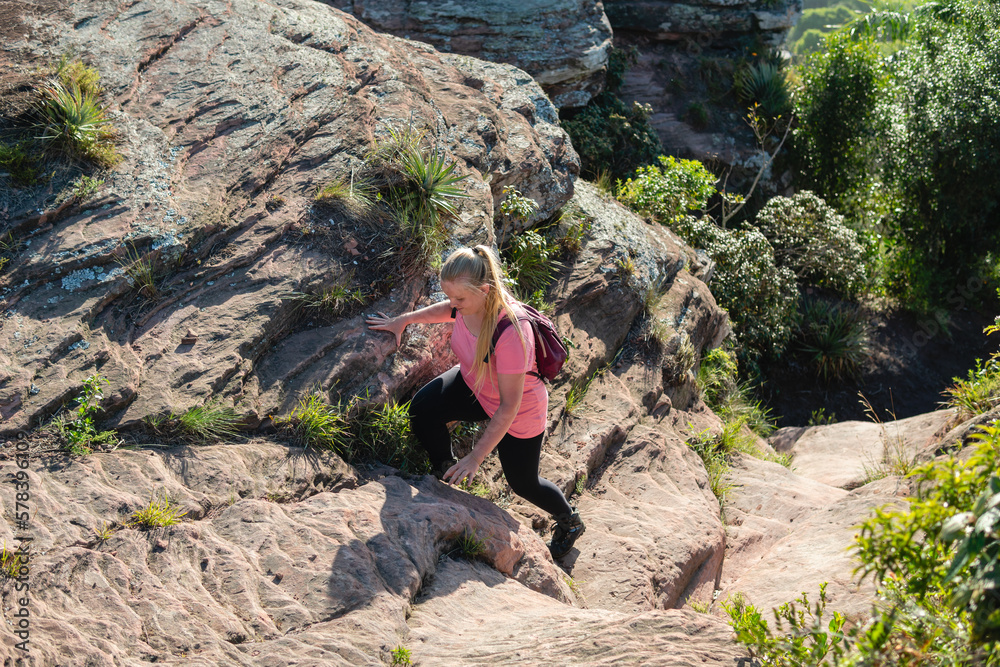 adventurous woman climbing rock in the forest
