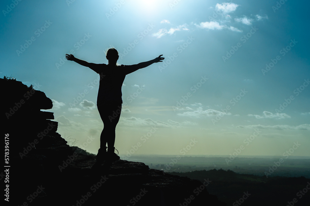 silhouette of woman enjoying view on top of rock with arms wide open in the forest silhouette of woman enjoying view on top of rock with arms wide open in the forest