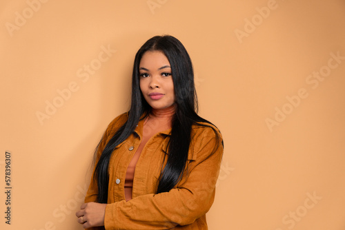 confident black woman with arms crossed in beige colors. portrait, real people concept.