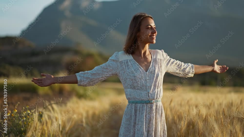 Beautiful freedom woman enjoying life in wheat field in summer sunset light. Nature beauty, mountains and field with golden wheat. people, agriculture and harvest