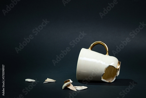 Broken tea cup isolated on black background. Cracked coffee mug and fragile ceramic pieces