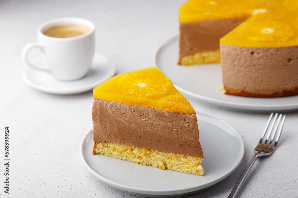 Chocolate-orange mousse cake with biscuit base, jelly and orange circles. Piece of homemade cheesecake and a cup of coffee. Traditional holiday dessert. Selective focus, close-up. Chocolate-orange mousse cake with biscuit base, jelly and orange circles. Piece of homemade cheesecake and a cup of coffee. Traditional holiday dessert. Selective focus, close-up.