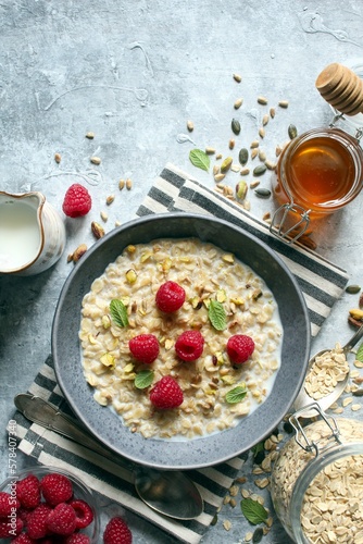 Healthy breakfast. Oatmeal porridge with raspberries, sunflower seeds, pistachio and honey. Top view.