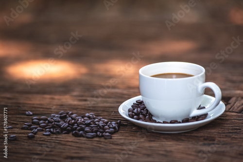 black drip coffee in ceramic cup on old wood table with coffee bean. Barista serve cup of hot black coffee on old wooden table cafe shop in garden with coffee bean.