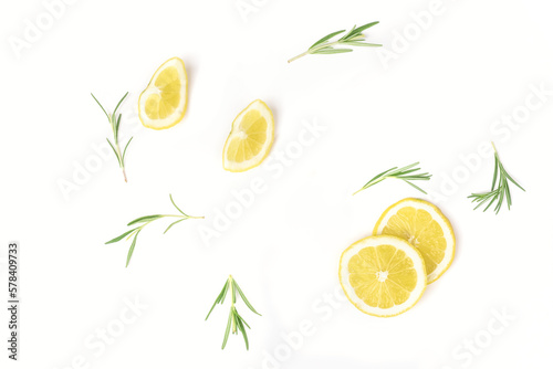 Lemon slices and rosemary arranged on a white background. Top view.