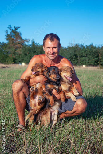 A man holds in his hands three small dogs in nature. Friendship of man and dogs.