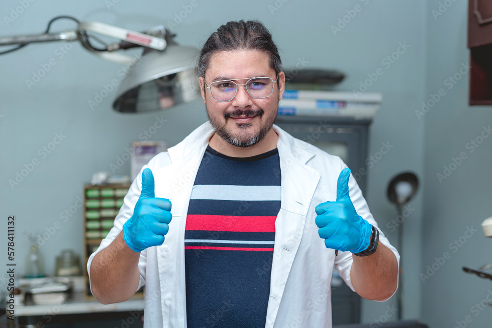 A local practicing male doctor in his late 30s running a small animal bite center or small clinic. Making a double thumbs up after a long day. A local practicing male doctor in his late 30s running a small animal bite center or small clinic. Making a double thumbs up after a long day.