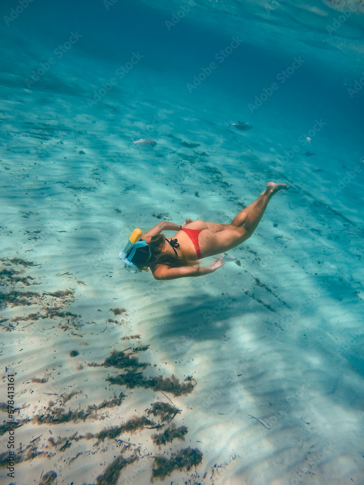 Young blonde woman in red swimsuit snorkeling in the beautiful waters of the mediterranean sea. 