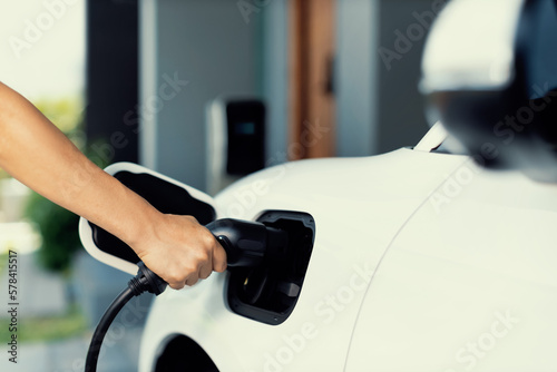Progressive concept of hand insert an emission-free power connector to the battery of electric vehicle at home. Electric vehicle charging via cable from charging station to EV car battery