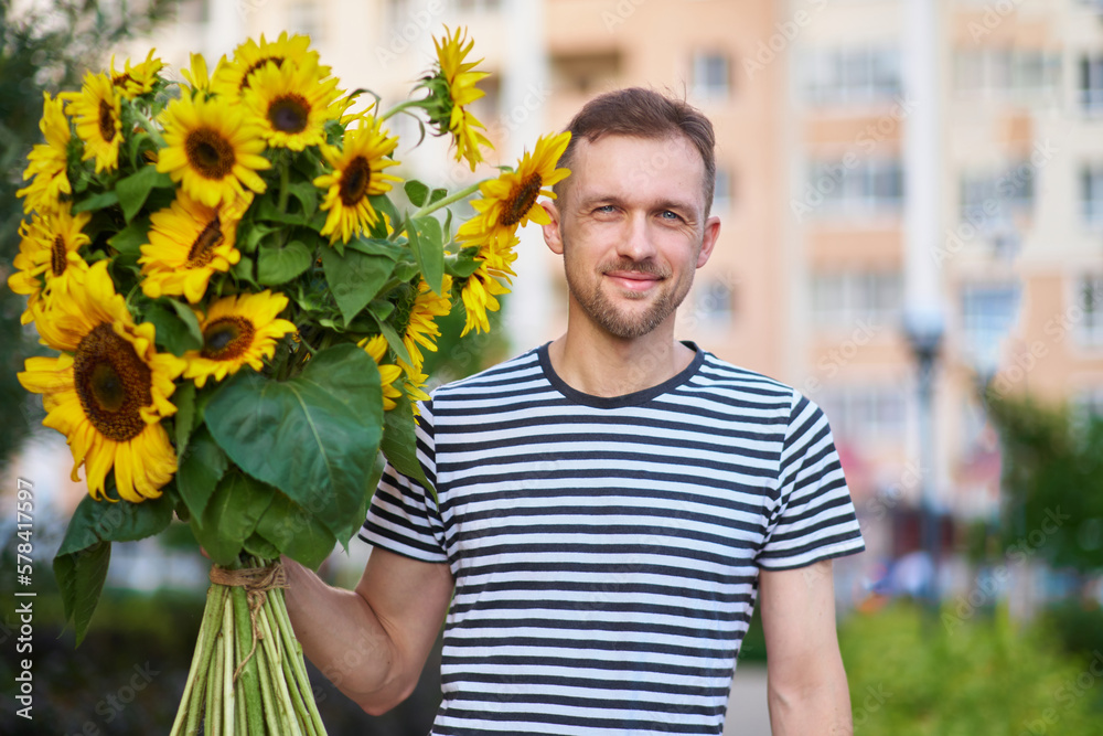 bouquet of yellow sunflowers in hands of a smiling happy man outdoor. Patriotic gift with love, gratitude. Mothers Day. Support for Ukraine. Independence Day. High quality photo