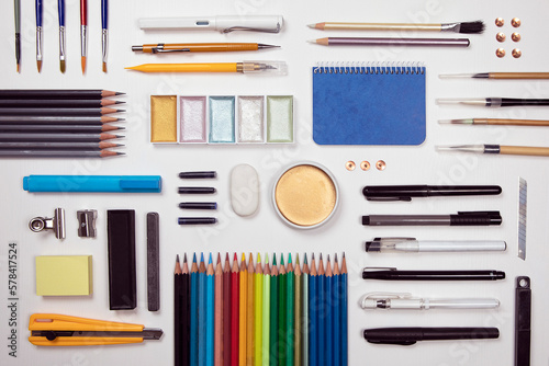 Designer work tools flat lay composition on white background. Painting, sketching, drawing activity, prepared work space. Objects as watercolors, paint brush, pencil, marker, pen and more supply.
