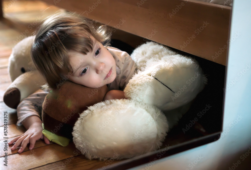 Girl looking herself in a mirror while lying on her teddy bear at home