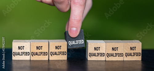 Symbol for finding a qualified candidate. Hand picks wooden cube with the text 'qualified' instead of cubes with the text 'not qualified'. photo