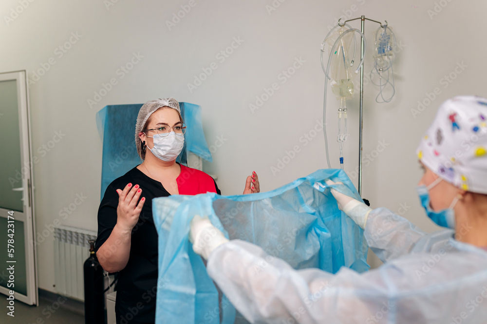 Nurse ties a sterile gown to the surgeon before the operation. Doctors