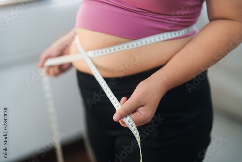 Close up overweight woman measuring her hip with tape measure.. photo