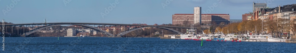 Panorama, the bay Riddarfjärden with long bridge Västerbron and the pier Norr Mälarstrand with moored tug and fishing boats, a sunny spring day in Stockholm