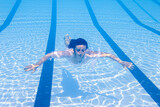 young girl in swimsuit floating on azure water of swimming pool in sunlight