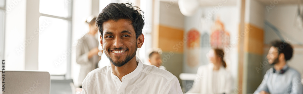 Smiling Businessman working laptop while sitting in modern office on colleagues background Smiling Businessman working laptop while sitting in modern office on colleagues background