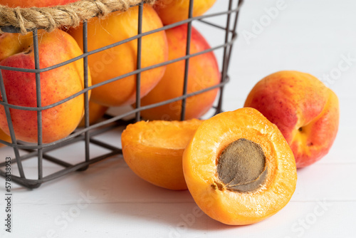 Sliced and whole apricots on a minimal basket with white and bright background. Pile of a fresh bio apricots.