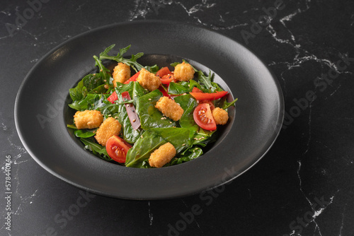 Salad with vegetables, arugula, avocado and fried tofu - close-up, copy space, modern vegetarian healthy cuisine,