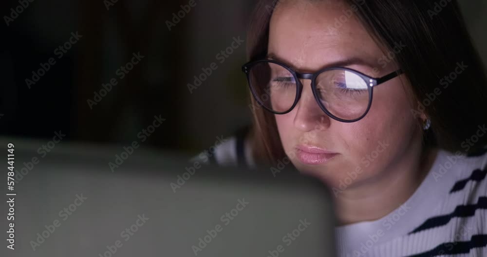 A focused woman in glasses looking at laptop screen with using internet A focused woman in glasses looking at laptop screen with using internet
