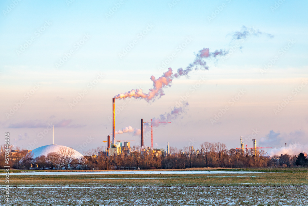 Fototapeta premium industry complex in Frankfurt in late evening with fields and smoking chimney