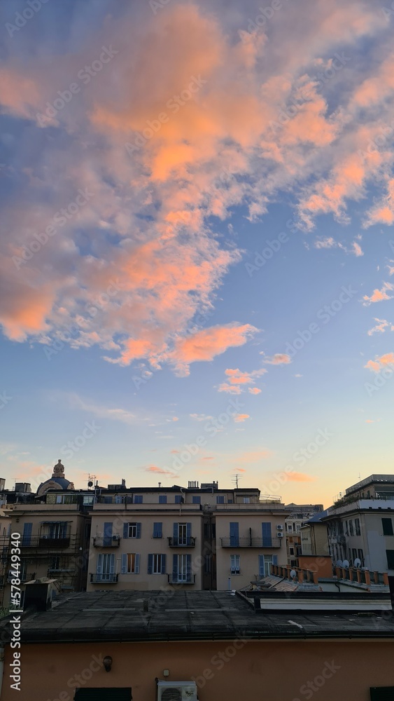 Genova, Italy - Januaru 27, 2023: Dramatic sky with orange clouds over the city before dawn or sunset. Weather before or after a storm.