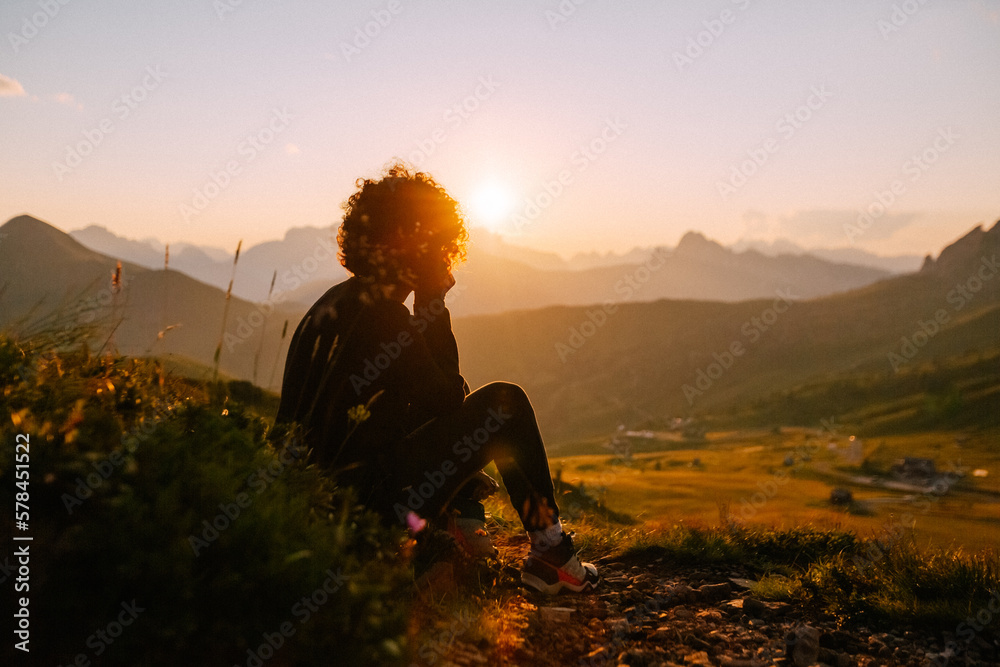 Berg-Panorama in den Alpen bei Sonnenuntergang im Sommer mit Silhouette einer sitzenden Frau - obrazy, fototapety, plakaty 