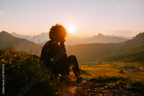 Berg-Panorama in den Alpen bei Sonnenuntergang im Sommer mit Silhouette einer sitzenden Frau