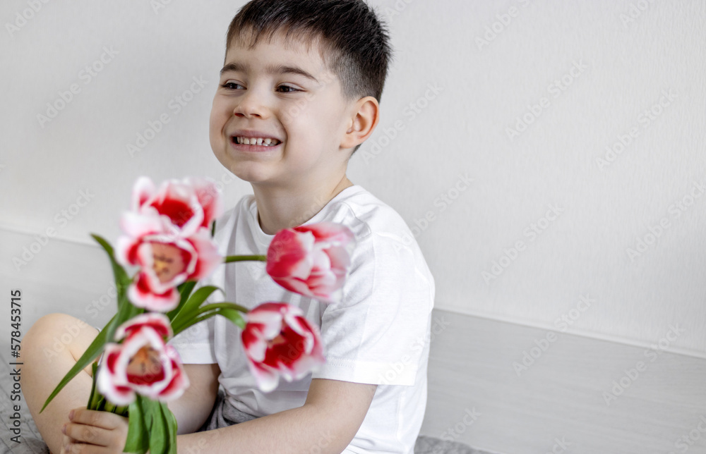 cute kid with bouquet of red tulips gift for mother women's day.child holding 2 tulips on eyes smiling having fun smelling one flower sitting on bed.birthday flowers easter spring coming preschooler cute kid with bouquet of red tulips gift for mother women's day.child holding 2 tulips on eyes smiling having fun smelling one flower sitting on bed.birthday flowers easter spring coming preschooler