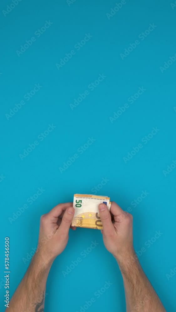 Vidéo verticale d'une personne qui manipule des billets de banque en euros, bras nus sur un fond bleu