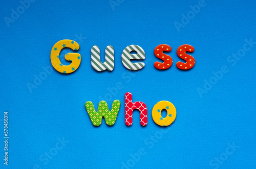 text guess who from bright colored paper letters on blue paper background photo