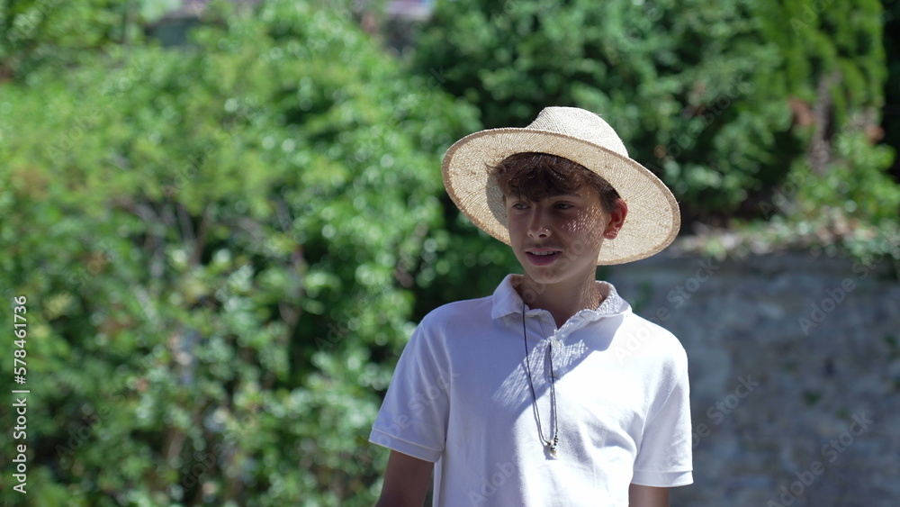 Teenager boy wearing fashionable Panama Hat standing outside during summer day. Handsome male kid in sunny day