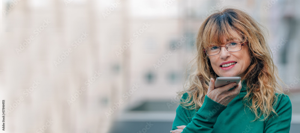 middle aged woman sending voice or audio message with mobile phone or smartphone middle aged woman sending voice or audio message with mobile phone or smartphone