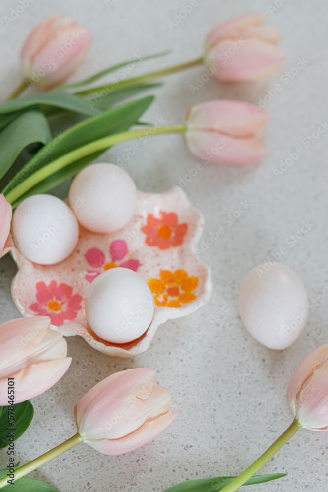 Beautiful tulips and natural eggs on modern table. Stylish easter still life with copy space. Happy Easter! Handmade egg holder with pink tulips