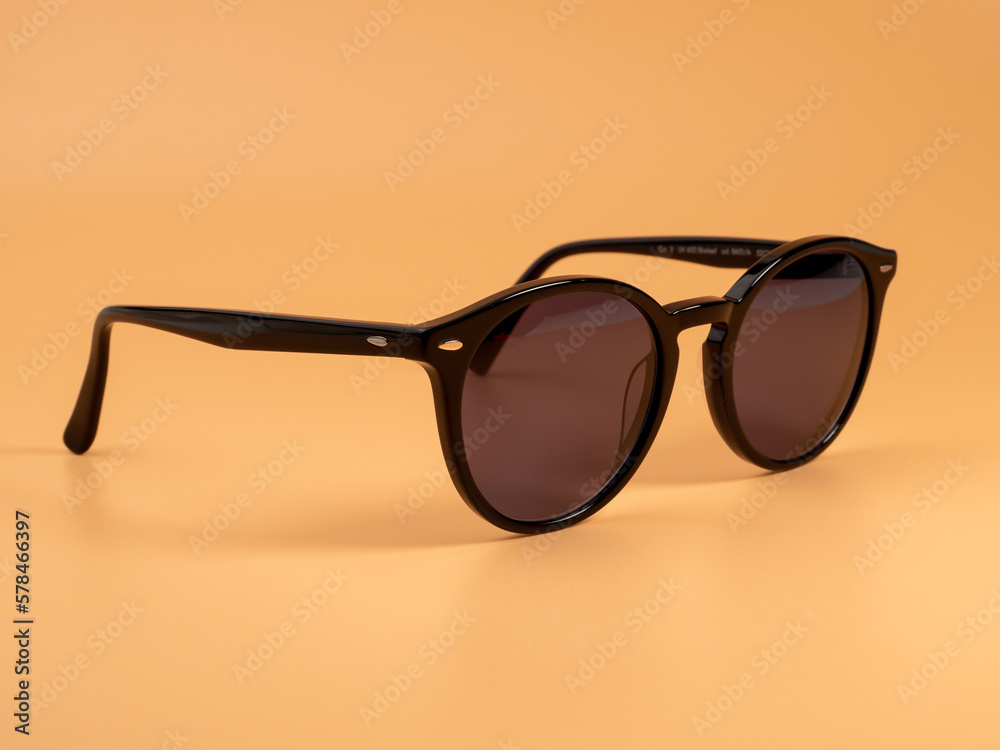 Stylish sunglasses. Sunglasses in a dark frame on an orange background. Close-up. Stylish sunglasses. Sunglasses in a dark frame on an orange background. Close-up.