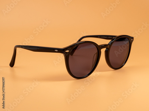 Stylish sunglasses. Sunglasses in a dark frame on an orange background. Close-up.