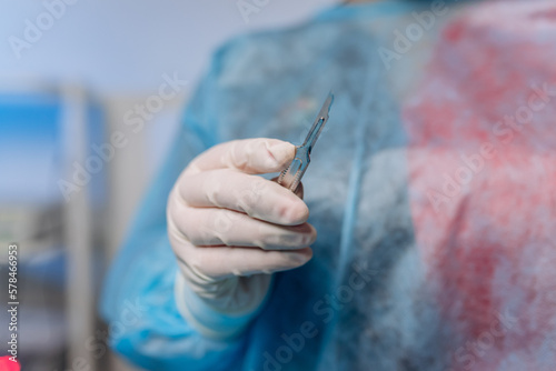 Professional doctor surgeon holding scalpel in operation room at hospital. Medical and pharmaceutical concept. Scalpel surgeon's scissors, just before surgery
