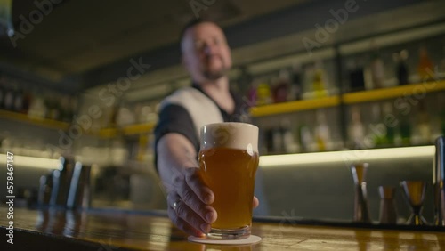 The bartender puts a glass of beer on the counter. A party in a pub with ale lager and wheat beer. High quality 4k footage