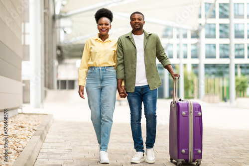 Black Travelers Couple Holding Hands Walking With Suitcase Outdoors