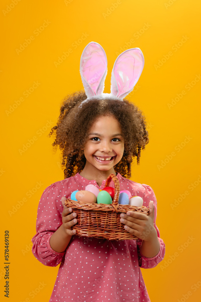 A Black girl with rabbit ears on her head with a basket full of colored eggs.