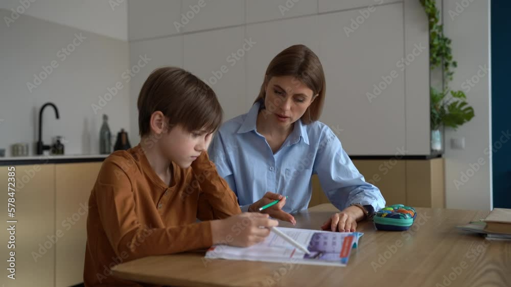 Upset stressed child boy feeling frustrated while doing homework with mom at home. Kid sitting at kitchen table with teacher tutor having difficulties in learning. Problems with homeschooling Upset stressed child boy feeling frustrated while doing homework with mom at home. Kid sitting at kitchen table with teacher tutor having difficulties in learning. Problems with homeschooling