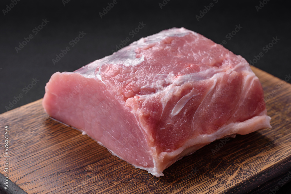 Fresh juicy pork on a wooden cutting board with spices and salt Fresh juicy pork on a wooden cutting board with spices and salt