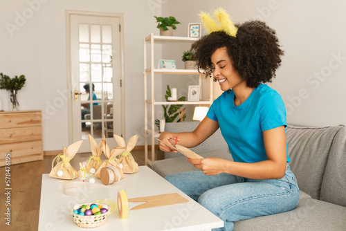 Happy black woman making handmade easter gift packaging at home