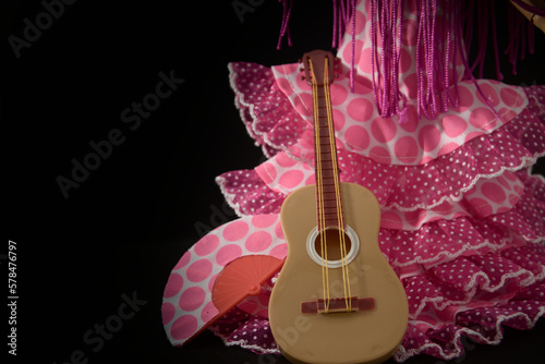 Flamenco woman's dress or faralaes, a guitar and a fan on black background with copy space photo