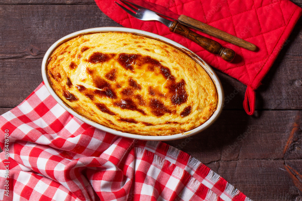 Cottage cheese casserole in an oval ceramic form on a wooden background. Rustic style.
