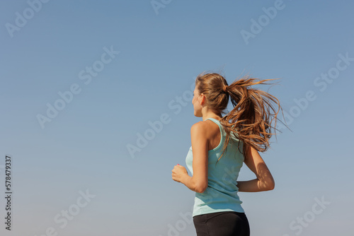 portrait of sporty woman jogging in morning on ocean. young confident woman runs to marathon and takes care of physical and mental condition. healthy lifestyle. fitness and yoga © MyJuly