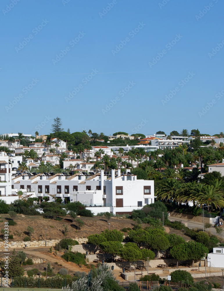 Holiday houses of white colour in the summer resort in Algarve, Portugal. Panoramic view from far. Verical photo