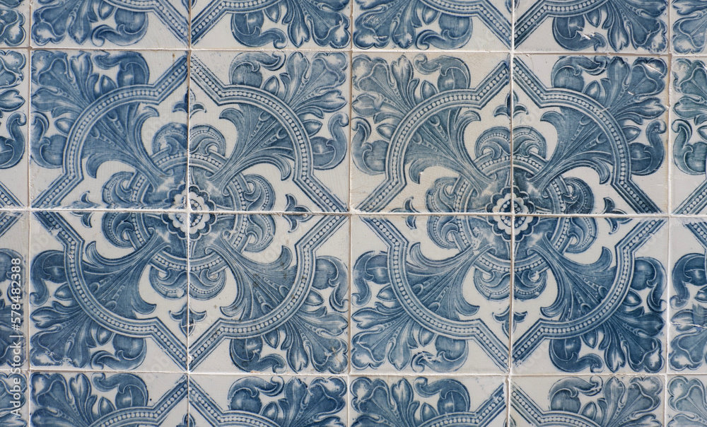 Vintage ceramic tiles of faded blue colour with floral repetitive ornate in Lisbon, Portugal. Authentic Portuguese tiling art